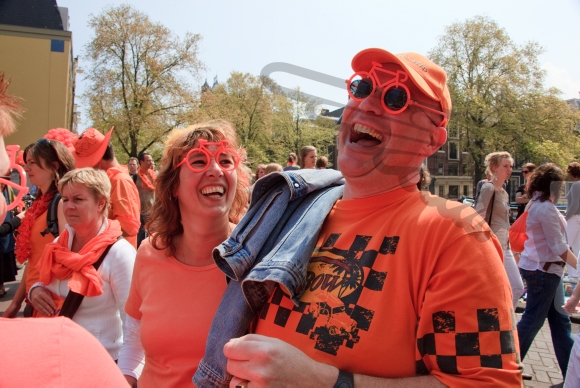 Orange couple laughing on a sunny day during the celebration of Queensday.