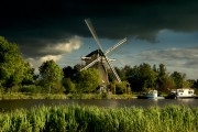 Windmill standing at the river with an imminent sky