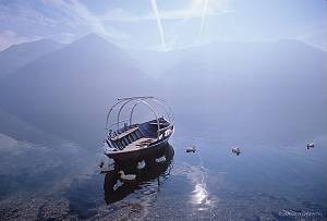 Switzerland, Tessin, Cima. A small fishing boat at Lake Lugano during the early morning.